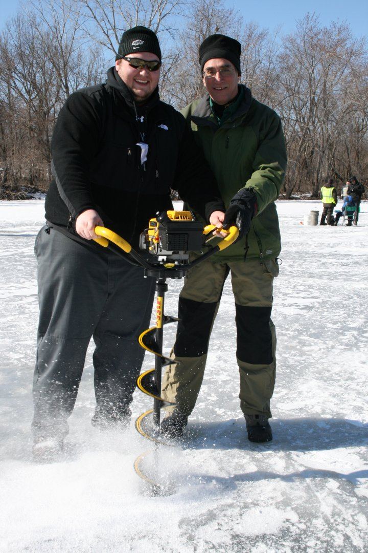 Two anglers drilling a hole through lake ice with a hand auger